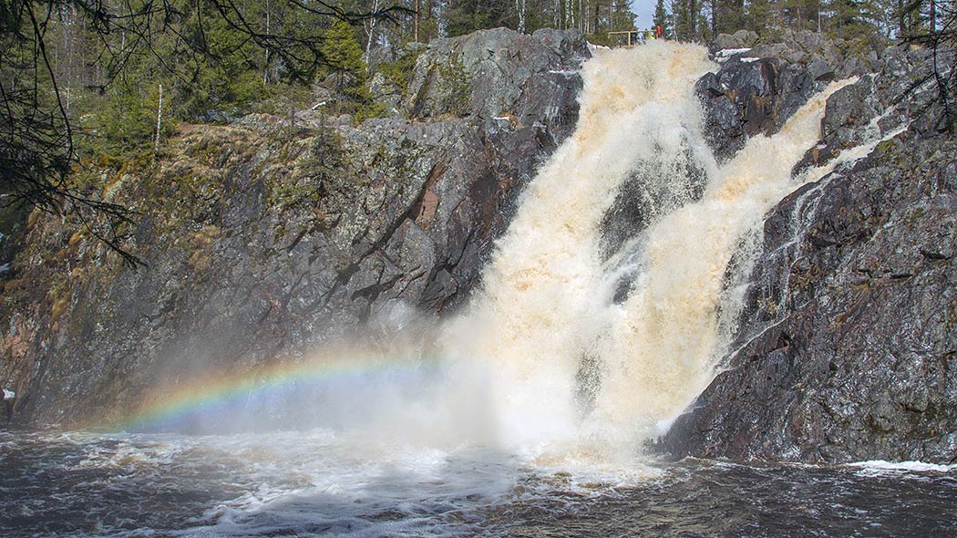 High bubbling rapids. People on a rock wall.